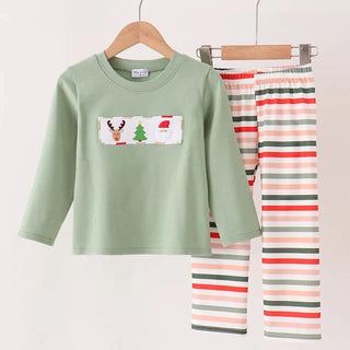 A children's two-piece pants set hanging on wooden hangers against a plain light background. The set includes a sage green long-sleeve top with a small Christmas-themed graphic on the chest, and matching striped pants in white with red, green, and gray horizontal stripes.