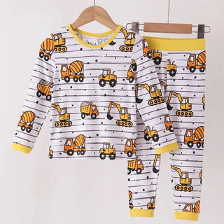 A two-piece boy pajama set featuring a long-sleeve top and matching pants, hanging on wooden hangers. The set has a white background with thin black stripes, a yellow collar and cuffs, and an all-over print of colorful construction vehicles (yellow, orange, and brown excavators and cement mixers).