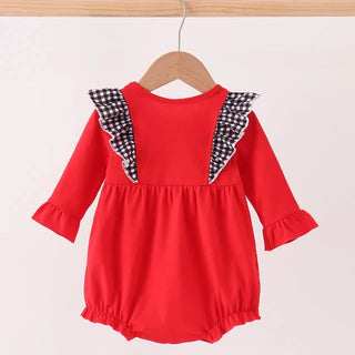 A red baby romper with three-quarter sleeves and black-and-white checkered ruffle details on the shoulders, hanging on a wooden hanger against a light background.