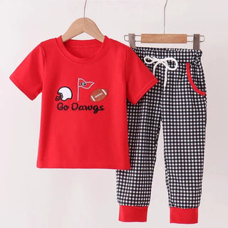 A two-piece kids' outfit hanging on wooden hangers against a light background. The set includes a bright red short-sleeve t-shirt with a football graphic and 'Go Dawgs' text, and black-and-white gingham check pants with red cuffs and red pocket trim.