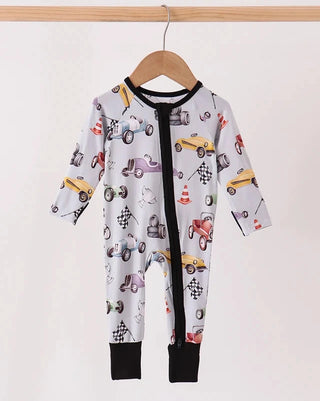 A baby long-sleeve footless one-piece jumpsuit with a front zipper, featuring a white background with a colorful race car pattern, hanging on a wooden hanger.