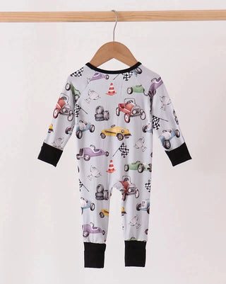 A baby long-sleeve footless one-piece jumpsuit with a colorful race car pattern, hanging on a wooden hanger from a light wood rod against a plain off-white background.