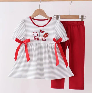 A toddler girl's two-piece outfit set hanging on wooden hangers against a plain light background. The set includes a white short-sleeve top with thin gray horizontal stripes, red trim at the collar and sleeve cuffs, red ribbon bows at the sides, and a 'Roll Tide' football graphic on the chest, paired with solid red leggings.