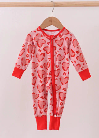 Baby onesie with heart pattern on a hanger against a white background