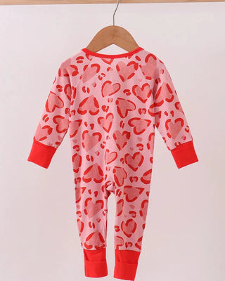 Children's onesie with red heart pattern on a hanger against a white background
