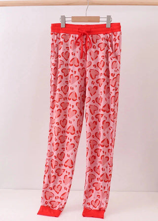Heart-patterned pajama pants on a hanger against a white background