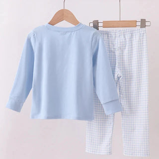 Children's light blue shirt and checkered pants on hangers against a white background