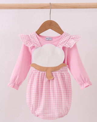 Pink baby romper with ruffled collar and checkered pattern on a wooden hanger against a light background