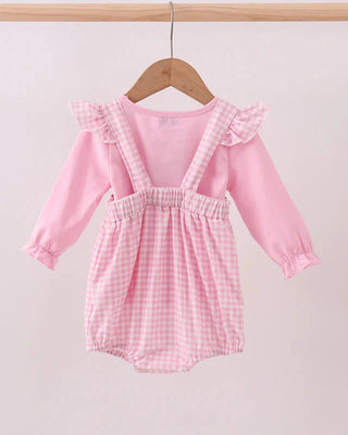 Pink baby romper with ruffled straps on a hanger against a light gray background