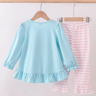 Light blue top and pink striped pants hanging on a rack against a white background