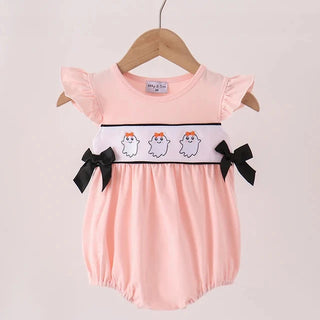 A baby romper in light pink, hanging on a wooden hanger. The romper features flutter sleeves, a smocked waistband with three cartoon ghosts and black stripes, and black bow accents on the sides.