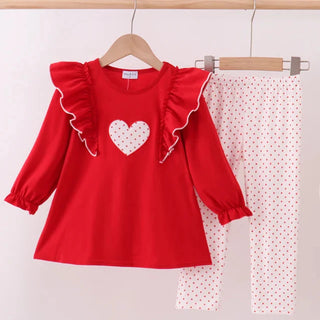Red top with white heart design and matching polka dot pants on a hanger against a light background