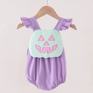 A baby girl's lavender romper with ruffled shoulder straps and a light green pumpkin applique on the chest featuring a pink jack-o'-lantern face, hanging on a wooden hanger.