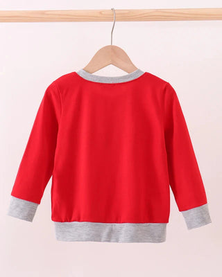 Red sweater with gray trim on a wooden hanger against a light pink background