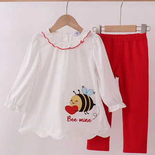 Children's outfit with white shirt and red pants on a hanger against a white background