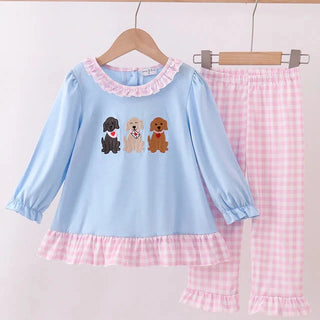 Children's outfit set with blue top and pink pants featuring dog illustrations on a white background.