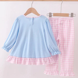 Children's outfit with blue top and pink checkered pants on a wooden hanger against a white background