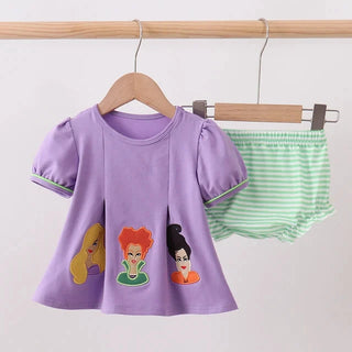 A children's outfit set hanging on a wooden rod, featuring a lavender short-sleeve dress with cartoon character patches and green-and-white striped diaper cover.