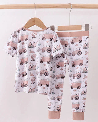 Children's pajama set with tractor pattern on a hanger against a white background