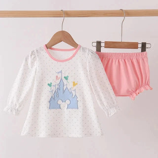 A children's two-piece outfit hanging on wooden hangers from a clothing rack. The set includes a white long-sleeve top with tiny light polka dots, a pink collar, and a blue castle graphic with a mouse head silhouette on the front, paired with pink ruffled bloomers.