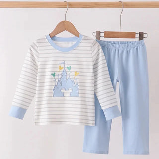 A two-piece children's pants set hanging on wooden hangers from a wooden rod. The set includes a long-sleeve top with white and light blue horizontal stripes, a light blue collar and cuffs, and a light blue castle graphic on the front, paired with matching light blue pants.