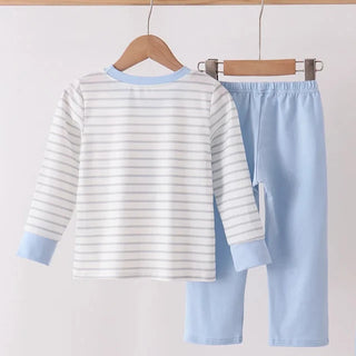 A two-piece children's pants set hanging on wooden hangers from a wooden rod. The set includes a long-sleeve top with thin gray horizontal stripes on a white background, light blue collar and cuffs, and solid light blue pants.