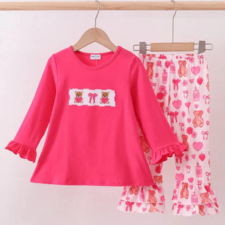 Pink children's outfit with teddy bear design on a white background