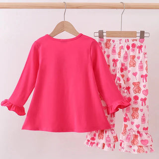 Pink long-sleeve top and patterned shorts on hangers against a white background