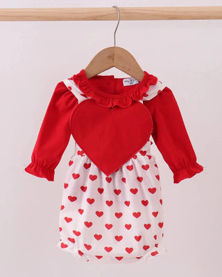 Red and white baby romper with heart patterns on a wooden hanger against a light background