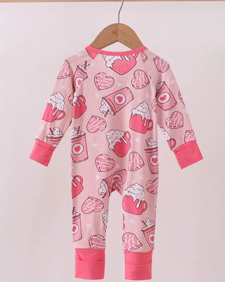 Pink baby onesie with heart coffee print on a hanger against a white background