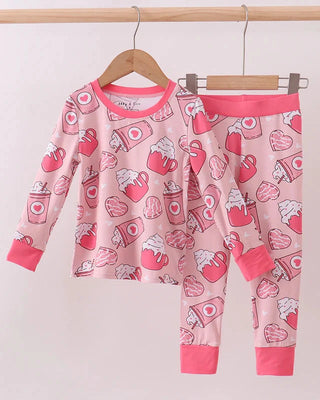 Children's pajama set with heart and coffee pattern on a hanger against a white background