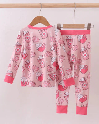 Pink children's pajama set with heart coffee print on a hanger against a white background