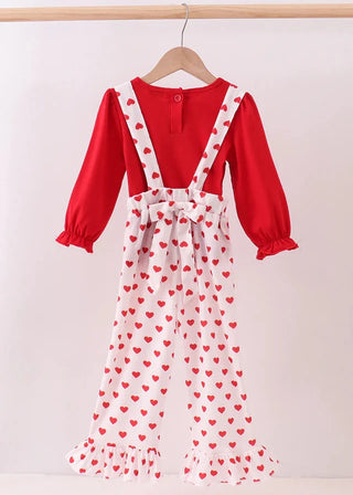 Red top with white jumpsuit featuring red heart patterns on a wooden hanger against a white background