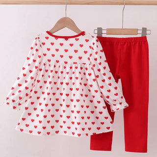 White blouse with red heart patterns and red pants on hangers against a white background