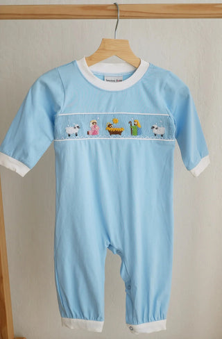 Light blue baby romper with embroidered design on a wooden hanger against a beige wall.