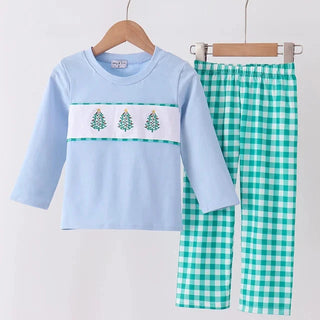 A two-piece children's pants set hanging on wooden hangers against a plain light background. The set includes a light blue long-sleeve top with a white chest band featuring three green pine trees, paired with green and white gingham pants.