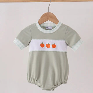A baby short-sleeve romper in sage green, featuring a white chest stripe with three orange embroidered pumpkins and a white gingham patterned cuff, hanging on a wooden hanger.
