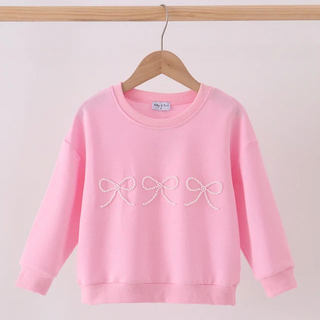 A light pink long-sleeve sweatshirt hanging on a wooden hanger against a plain light background. The sweatshirt features three white embroidered bow designs across the chest.