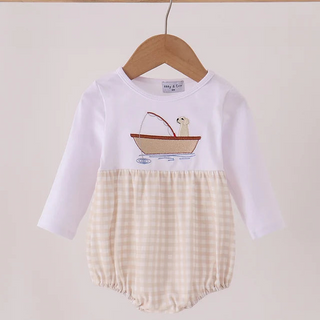 A baby long-sleeve romper hanging on a wooden hanger, featuring a white upper section with a boat graphic and a cream-and-beige gingham patterned lower section.