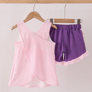 A two-piece children's outfit set hanging on wooden hangers against a plain light background. The set includes a sleeveless wrap-style top in light pink and white gingham pattern and matching purple shorts with a white ruffle trim.