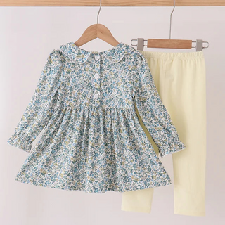 A toddler girl's two-piece outfit set hanging on wooden hangers against a plain light background. The set includes a long-sleeve floral print dress in light blue, white, and yellow, paired with solid pale yellow leggings.