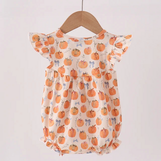 A baby romper with a pumpkin print hanging on a wooden hanger from a wooden clothes rack against a plain light background.
