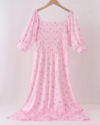 A light pink off-the-shoulder midi dress with a small floral print, hanging on a wooden hanger against a plain white background.