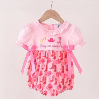A pink baby romper with short ruffled sleeves, a ruffled neckline, and a patterned lower half, hanging on a wooden hanger against a plain light background. The top features cowboy-themed graphics and the text 'Long Line Cowboy'.