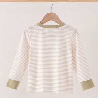 A long-sleeve boy top with thin beige and white horizontal stripes, featuring solid sage green trim at the crew neck and cuffs, hanging on a wooden hanger from a light wood bar.