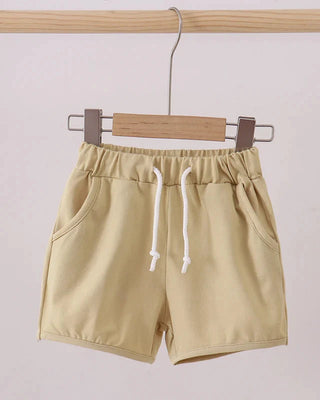 Beige shorts with a white drawstring on a wooden hanger against a light background