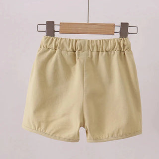 Beige shorts hanging on a wooden hanger against a light background
