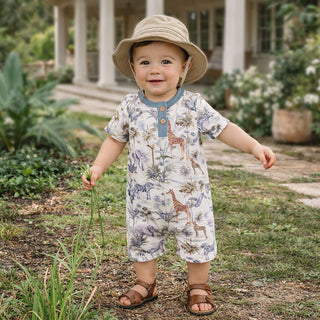 Child wearing a safari-themed romper and hat in a garden setting