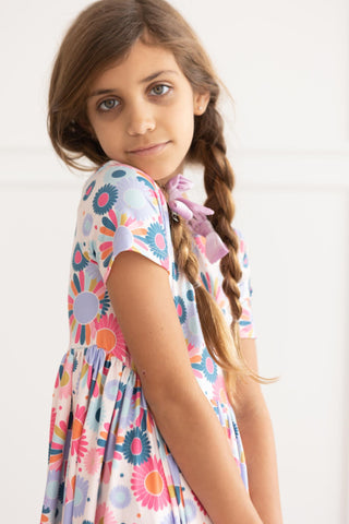Young girl wearing a colorful floral dress with a plain background