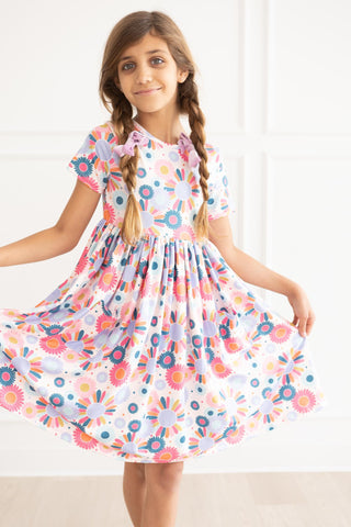 Young girl wearing a colorful floral dress against a white background